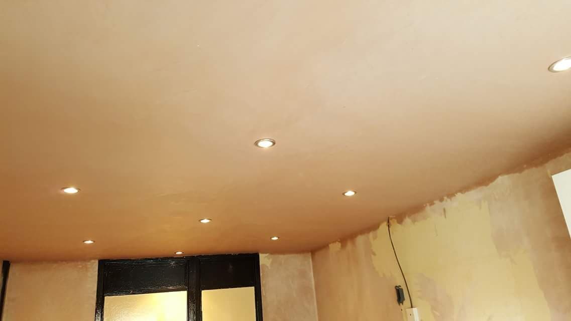Eight recessed downlights set out across a freshly plastered ceiling