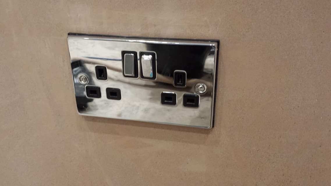 Chrome double socket with USB charging points, fitted flush to a plastered wall
